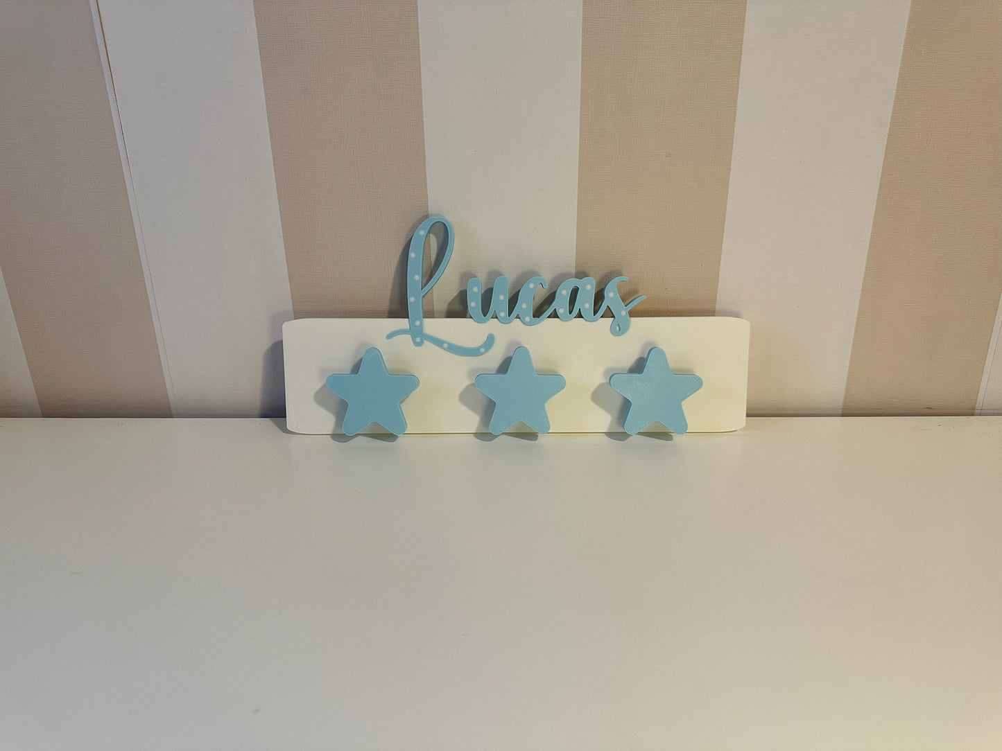 Percha pared infantil rectangular color azul con nombre personalizado en relieve y colgadores de estrellas para habitación niño