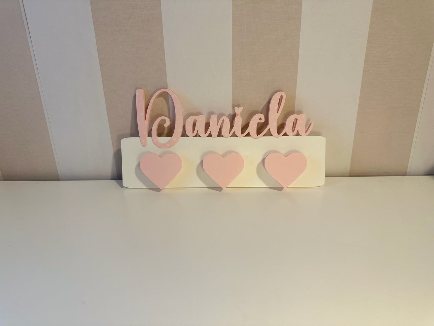 Percheros infantiles de pared personalizados instalados en habitación de niña con corazones rosas nombre Daniela