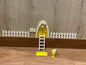 Puerta Ratón Pérez con puerta en miniatura amarillo, escalera, valla, cartel de bienvenida y queso, creando un escenario encantador en 3D sobre una superficie de madera.